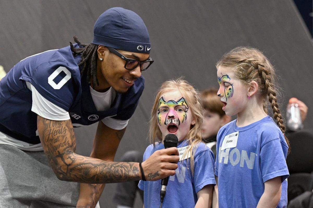 Penn State football player Chase Sowell holds the mic as he sings with Rylie and Fiona Eichelberger during the Thon Explorers event at the Lasch Building on Saturday, Feb. 21, 2026. 