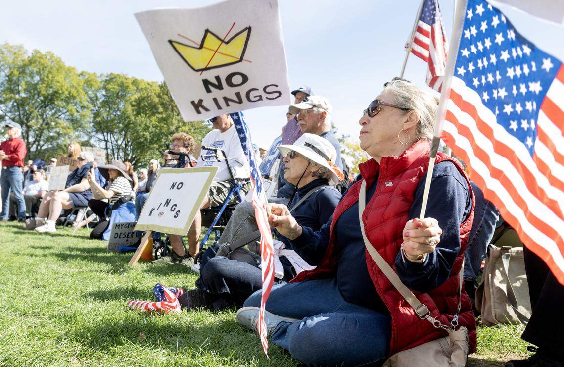 Jackie Sobel waves American flags with a No Kings sign as she listens to speakers at the No Kings anti-Trump rally on Saturday, Oct. 18, 2025. 