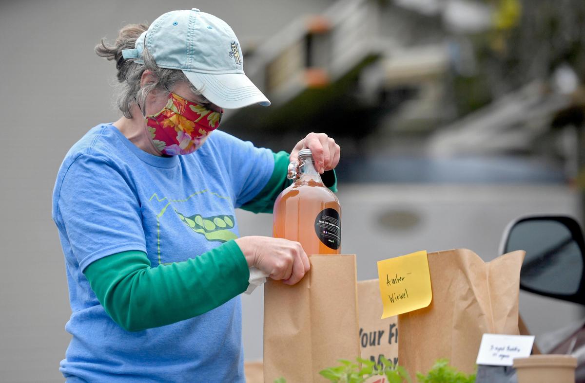 Sabine Carey packages Mount Nittanee kombucha for an online order at the Boalsburg Farmers Market on Tuesday April 28, 2020. During the pandemic, the market moved outside early and also offered online ordering.