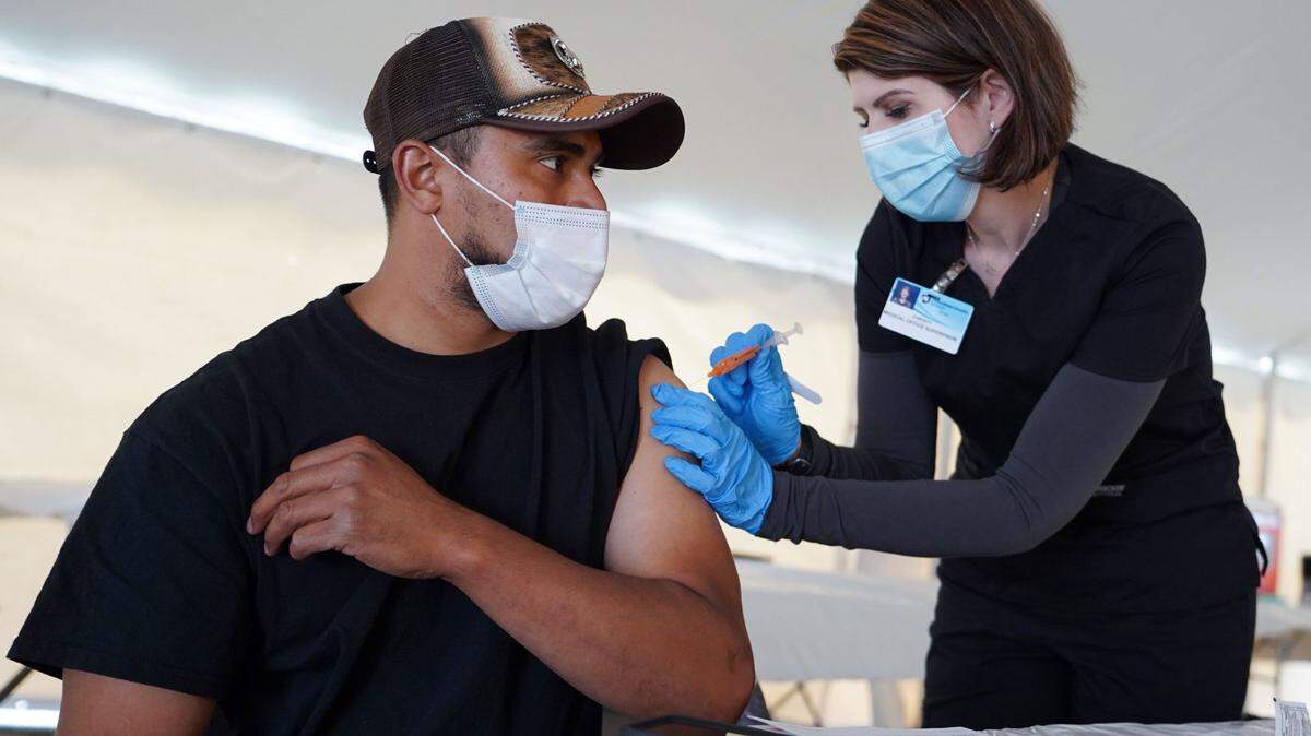 Giorgi Mushroom Company worker Juan Frutos gets a vaccine shot from Penn State Health nurse Christy Daniels during a clinic facilitated by Latino Connection’s mobile unit. The Wolf administration hired the group this spring to address persistent disparities.