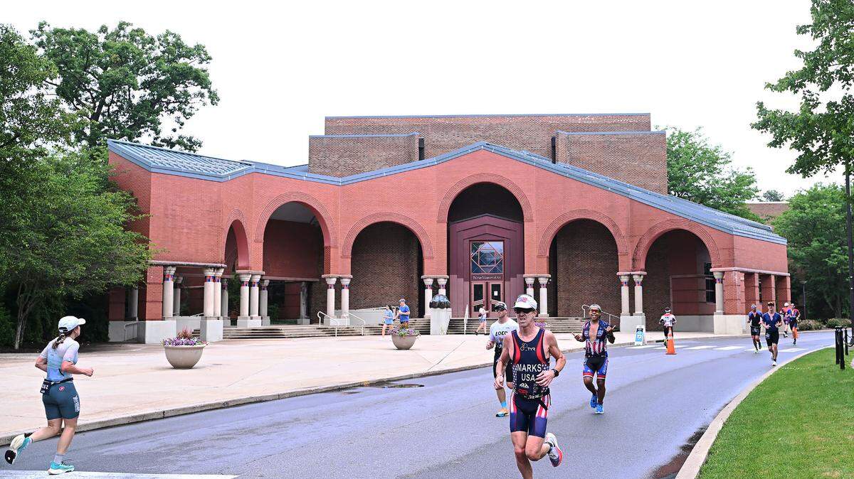 Participants in the Ironman 70.3 Pennsylvania Happy Valley run past the former Palmer Art Museum on the University Park campus Sunday, July 2, 2023.