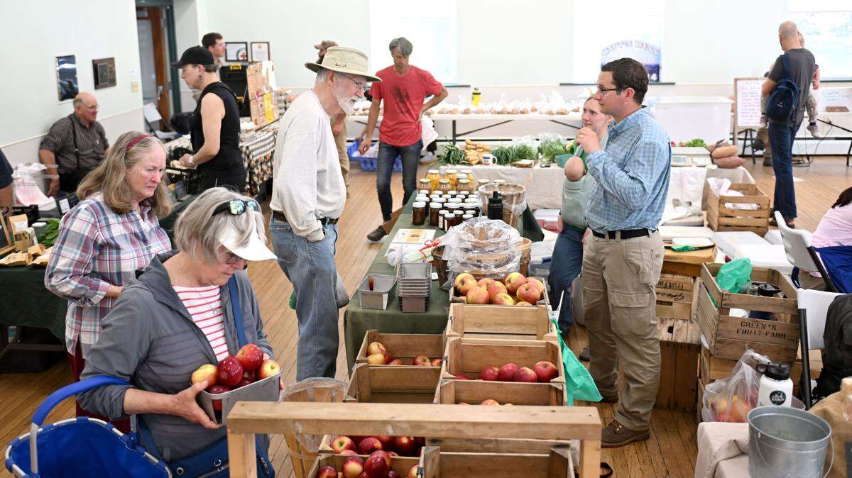 Visitors browse the apples and items from Green’s Fruit Farm during the Boalsburg Farmers Market at the Boalsburg Fire Company on Tuesday, April 29, 2025.