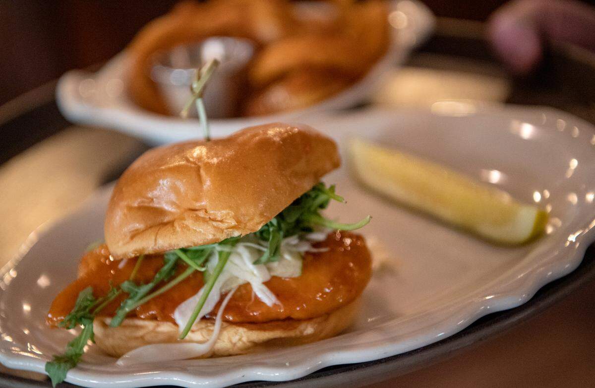 A fried chicken sandwich with a side of onion rings is delivered to a diner at The Corner Room on Thursday, Nov. 11, 2021.