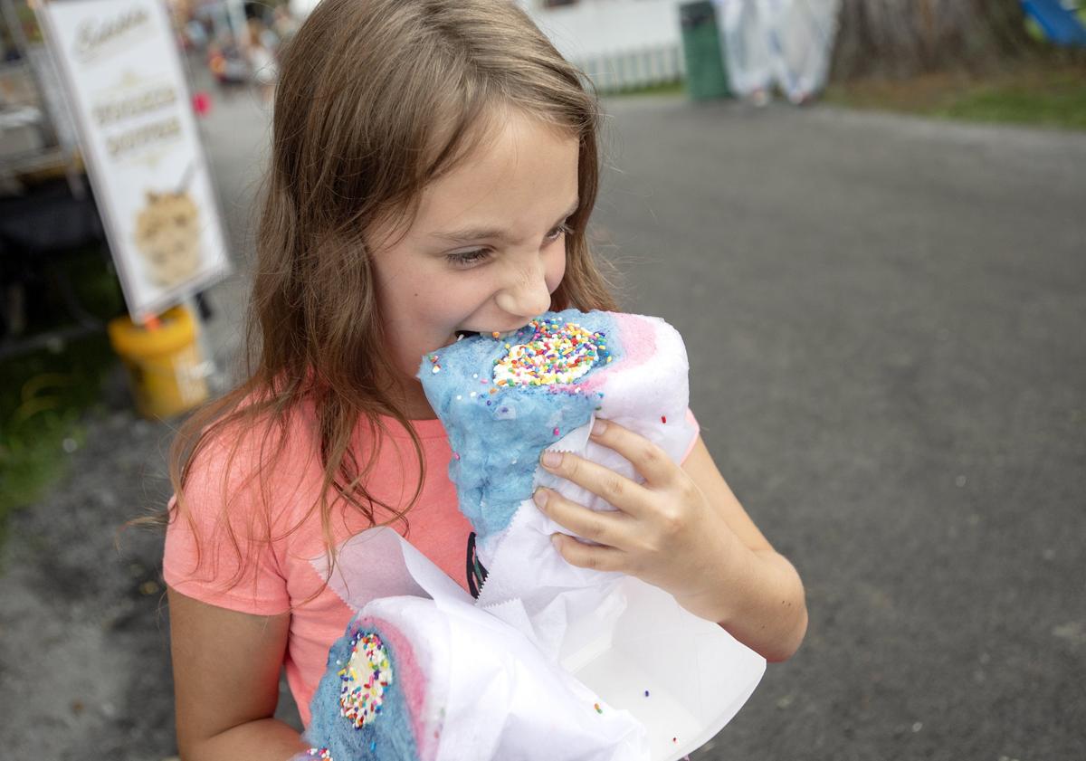 Claire Brownson, 9, bites into the Cotton Candy Burrito from Incredible Popcorn at the Centre County Grange Fair on Monday, August 20, 2018.  The new treat is layers of cotton candy, ice cream, a Twinkie and sprinkles.
