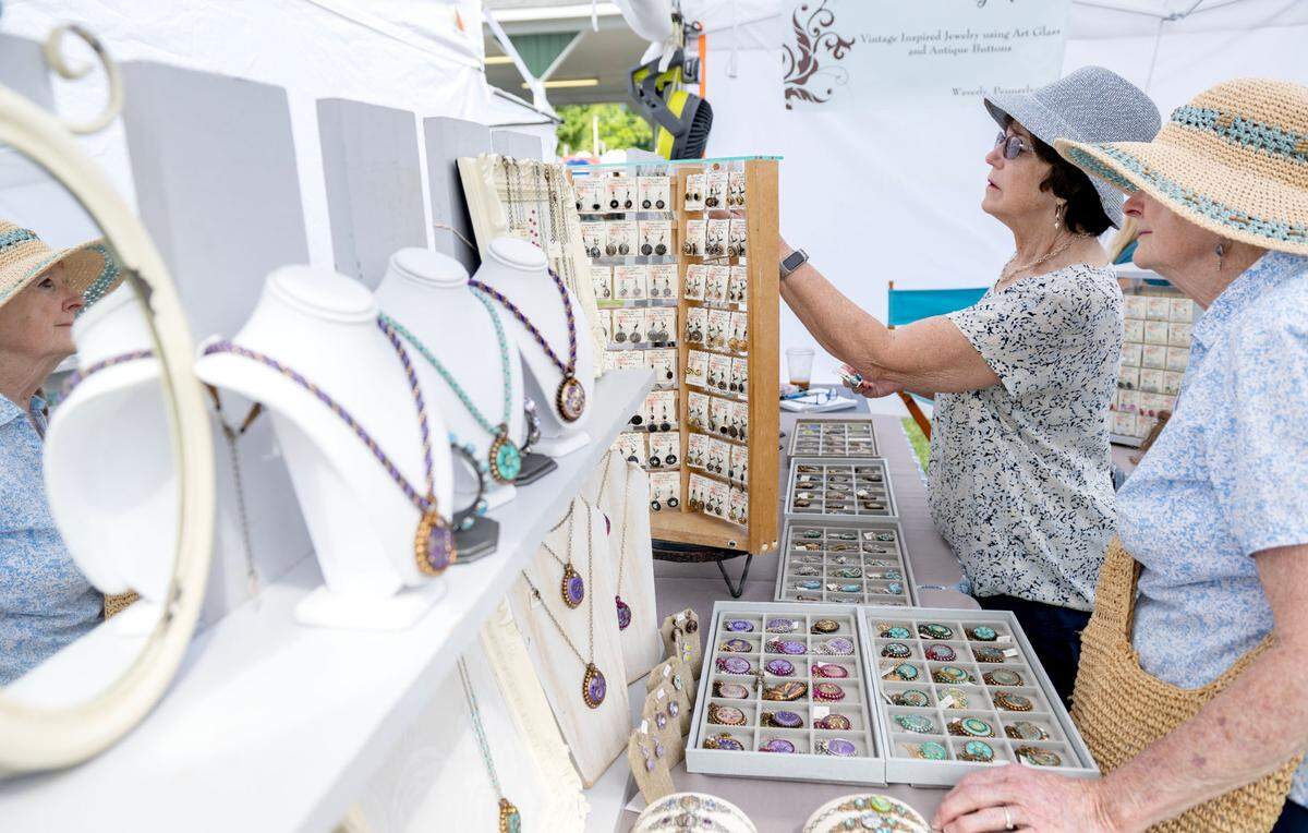 Visitors browse vintage inspired jewelry made with glass buttons at Vintage Charm By Monika’s booth at the People’s Choice Festival of Pennsylvania Arts & Crafts on Friday, July 12, 2024.