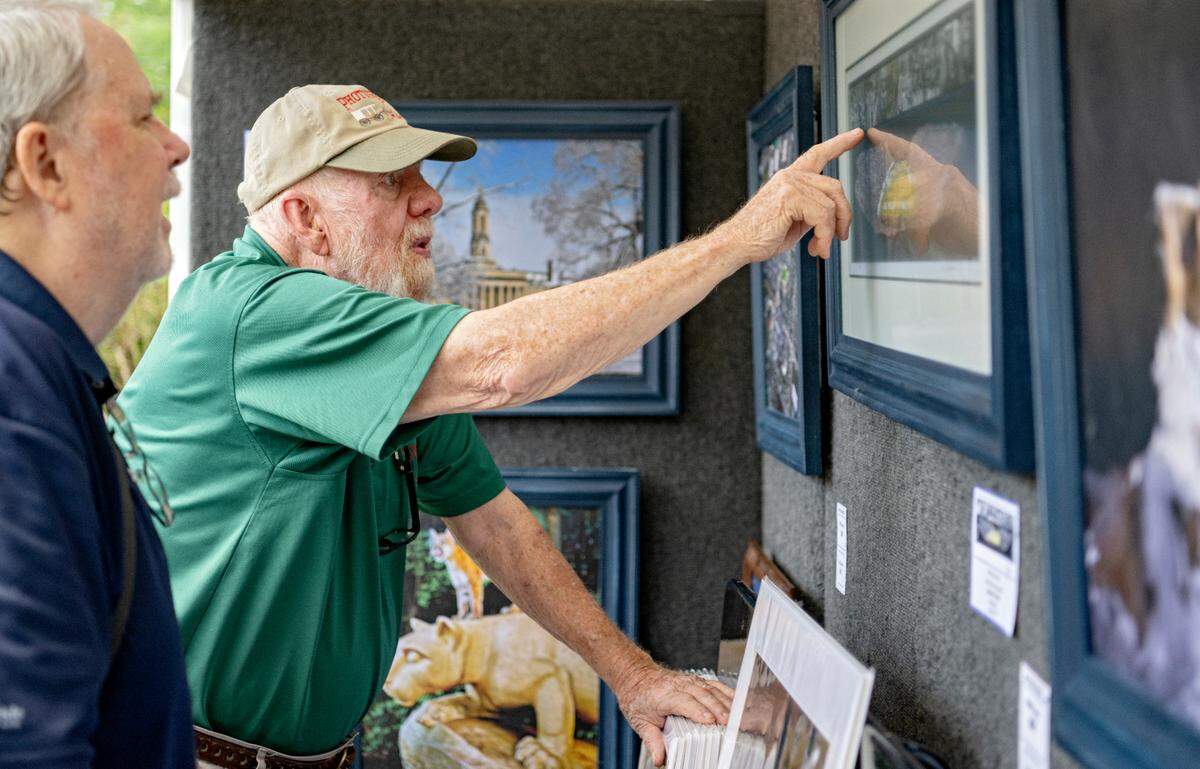 Dick Brown talks with a customer about a series of photographs at his booth during the Central Pennsylvania Festival of the Arts on Thursday, July 14, 2022.