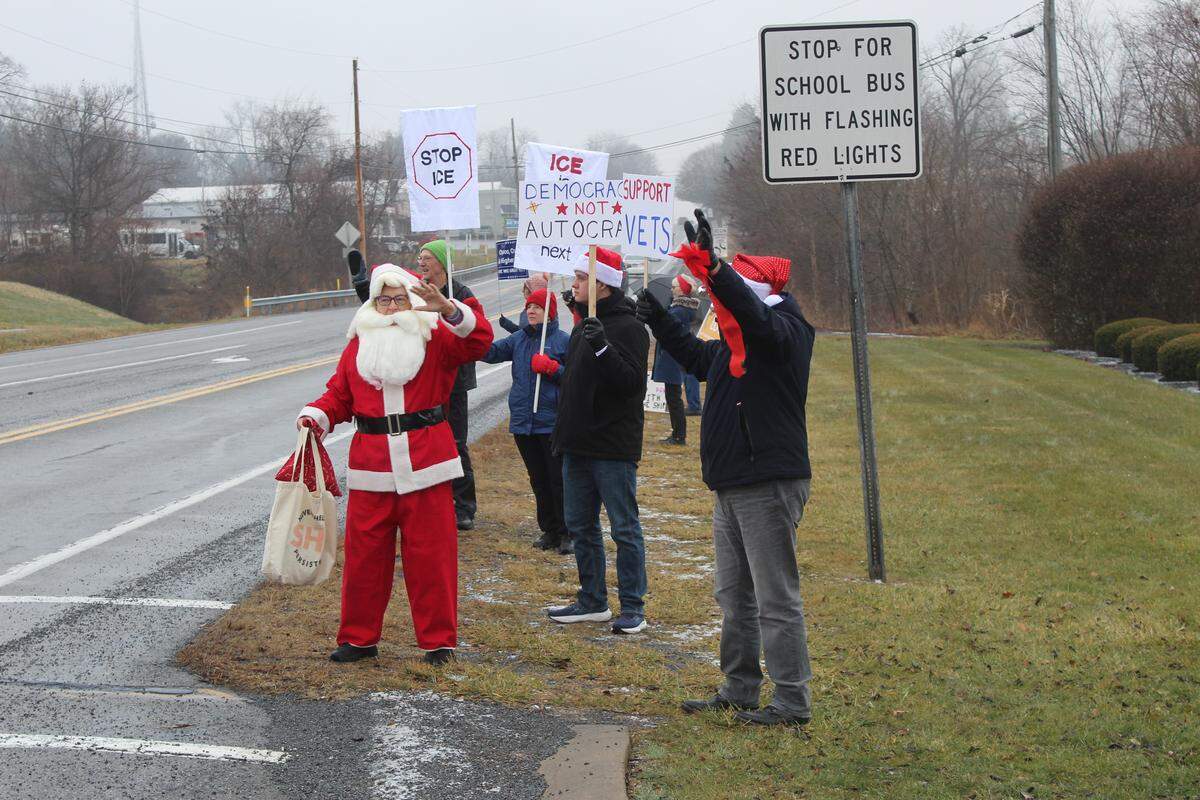 Keystone Indivisible member Dotty Delafield, dressed as Santa, and other protesters gather alongside the Benner Pike, in front of U.S. Rep. Glenn “GT” Thompson’s Bellefonte office, on Tuesday.