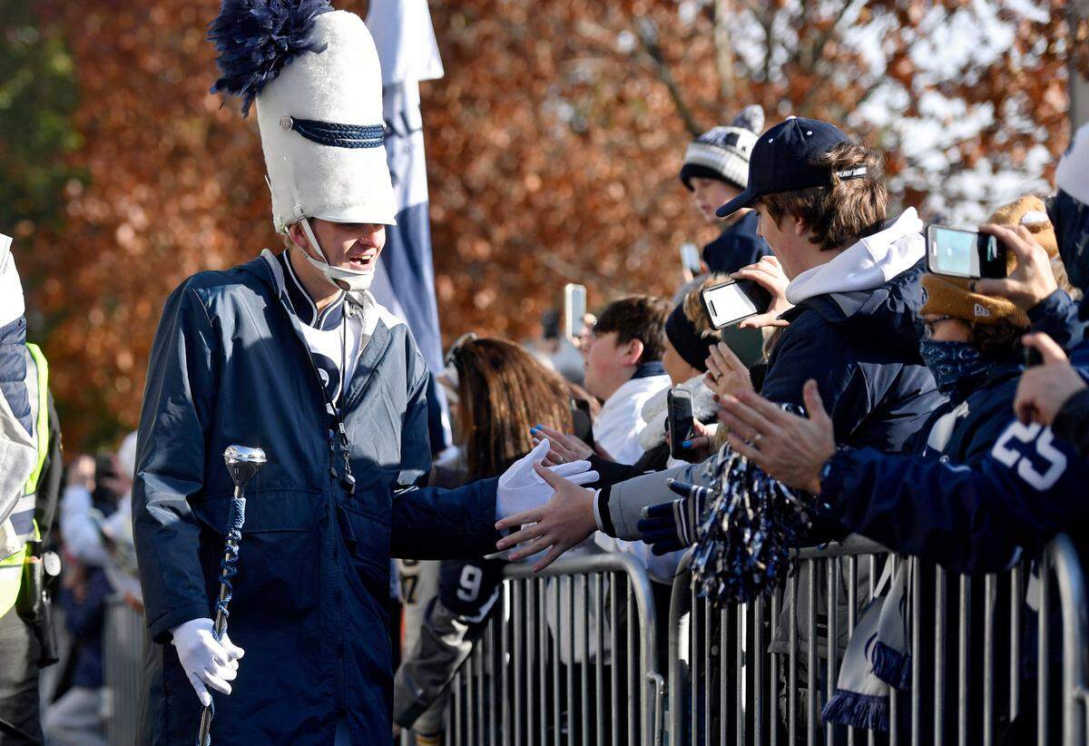 Penn State Blue Band drum major Ryan Frist high fives fans during team arrival on Saturday, Nov. 20, 2021.