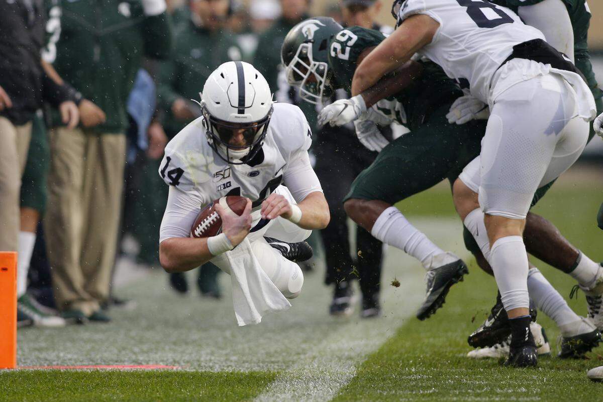 Penn State quarterback Sean Clifford, left, dives for a first down against Michigan State’s Shakur Brown (29) during the first quarter of an NCAA college football game, Saturday, Oct. 26, 2019, in East Lansing, Mich. (AP Photo/Al Goldis)