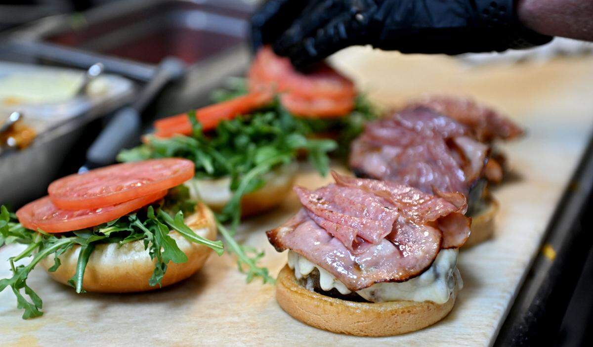 Executive Chef Bradley Hansen prepares several Coach Campbell’s Roman Burgers at The Field. The burger features salami, mortadella, white cheddar cheese, arugula, tomato, onion, mayonnaise and Italian dressing on a brioche bun.