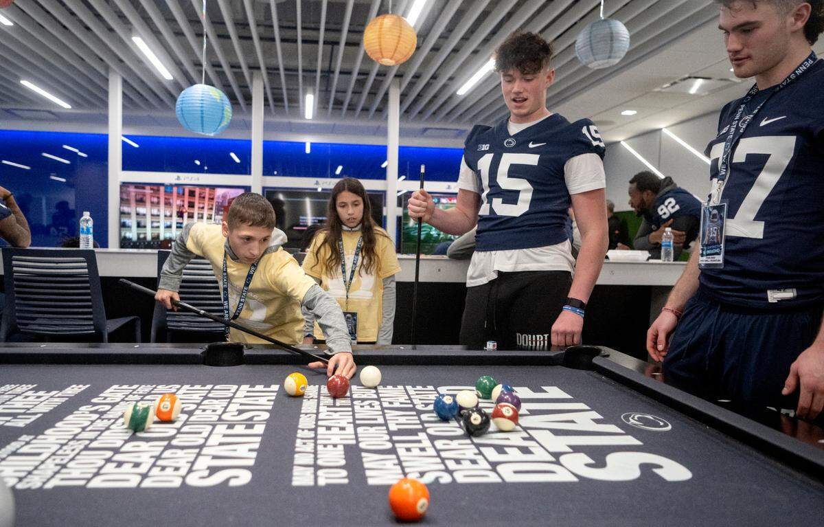 Daniel Testa, 14, plays pool with Penn State quarterback Drew Allar and other football players during the Thon Explorers program at the Lasch Building on Saturday, Feb. 18, 2023.