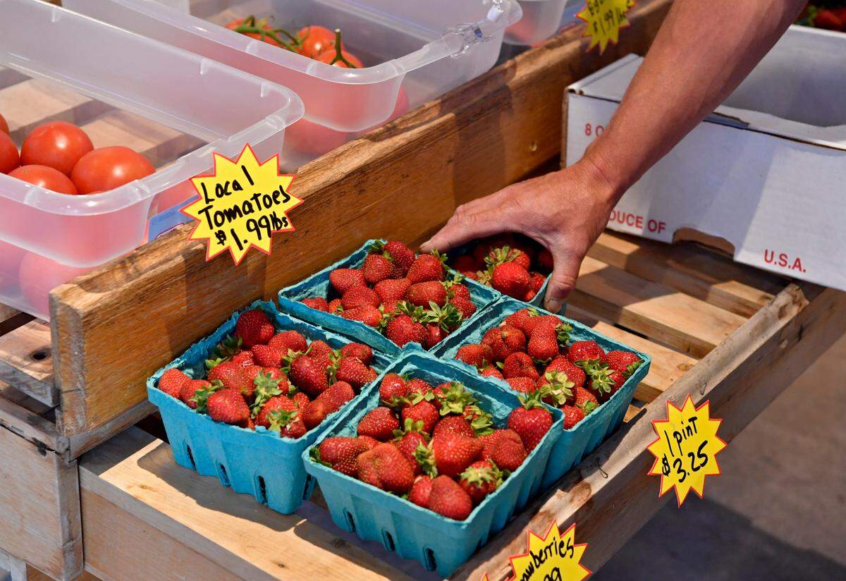Ojay Guenot places quarts and pints of local fresh strawberries at Nala May Farm and Nursery in Karthaus on Monday.
