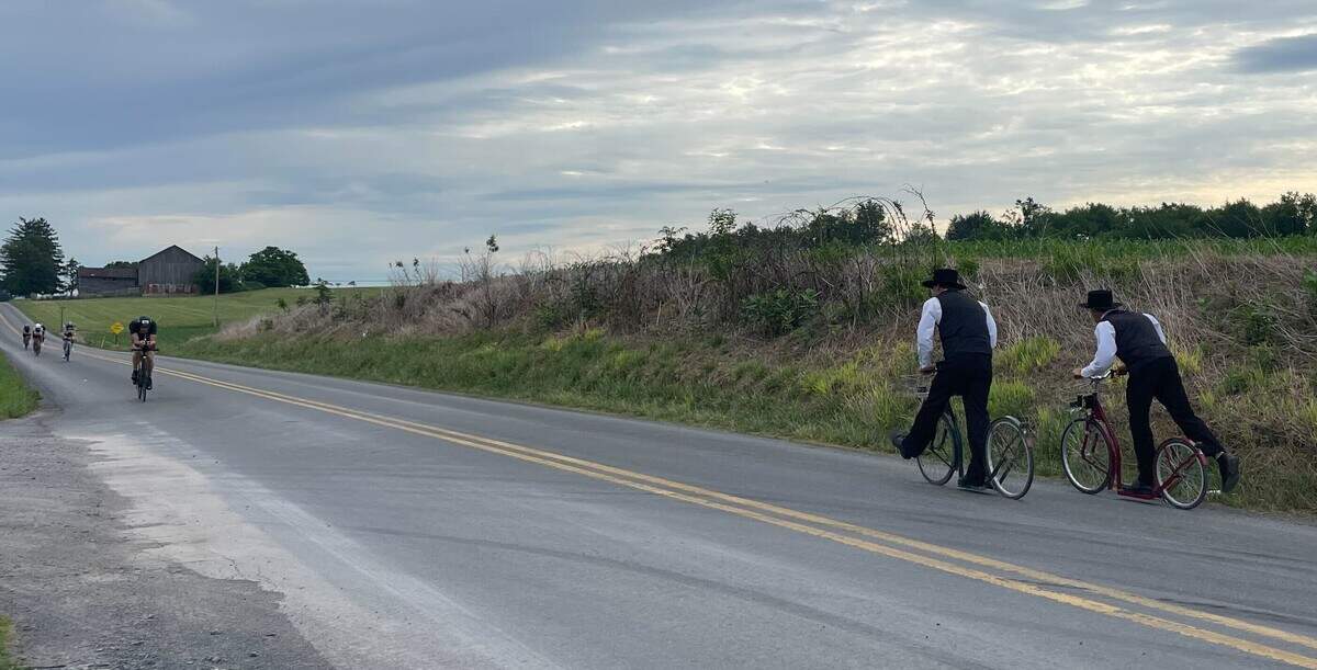 Some Amish pass cyclists, with Nico Spadavecchia in the lead, going the opposite way on Jacksonville Road on Sunday, June 14, 2026, during the Ironman 70.3 Pennsylvania Happy Valley North American Championship in Centre and Clinton counties.