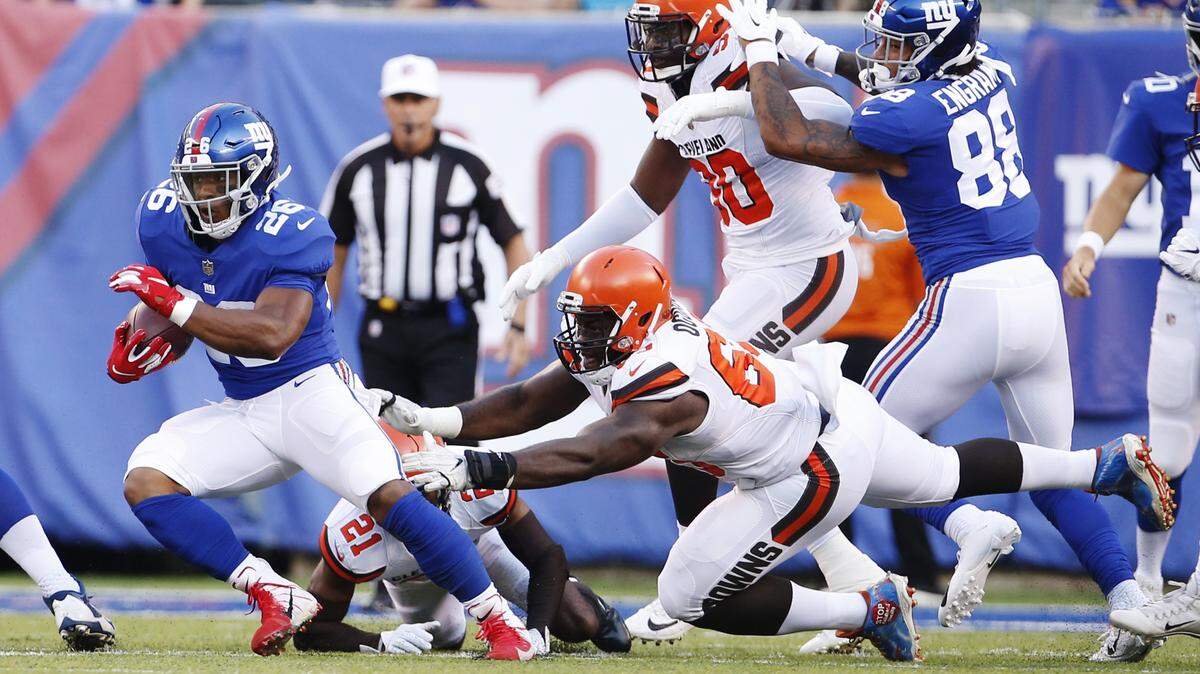 New York Giants running back Saquon Barkley (26) rushes past Cleveland Browns’ Larry Ogunjobi (65) during the first half of a preseason NFL football game Thursday, Aug. 9, 2018, in East Rutherford, N.J. (AP Photo/Adam Hunger)