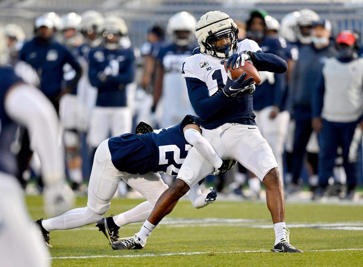 Penn State wide receiver Daniel George makes a catch as cornerback Jeffrey Davis Jr. goes for the tackle during practice on Friday, April 23, 2021 at Beaver Stadium.
