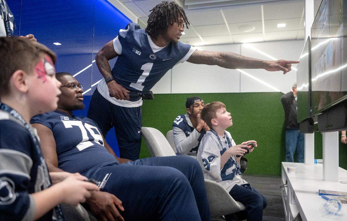 Penn State wide receiver KeAndre Lambert-Smith and a group of players play video games with youngsters during the Thon Explorers program at the Lasch Building on Saturday, Feb. 18, 2023.