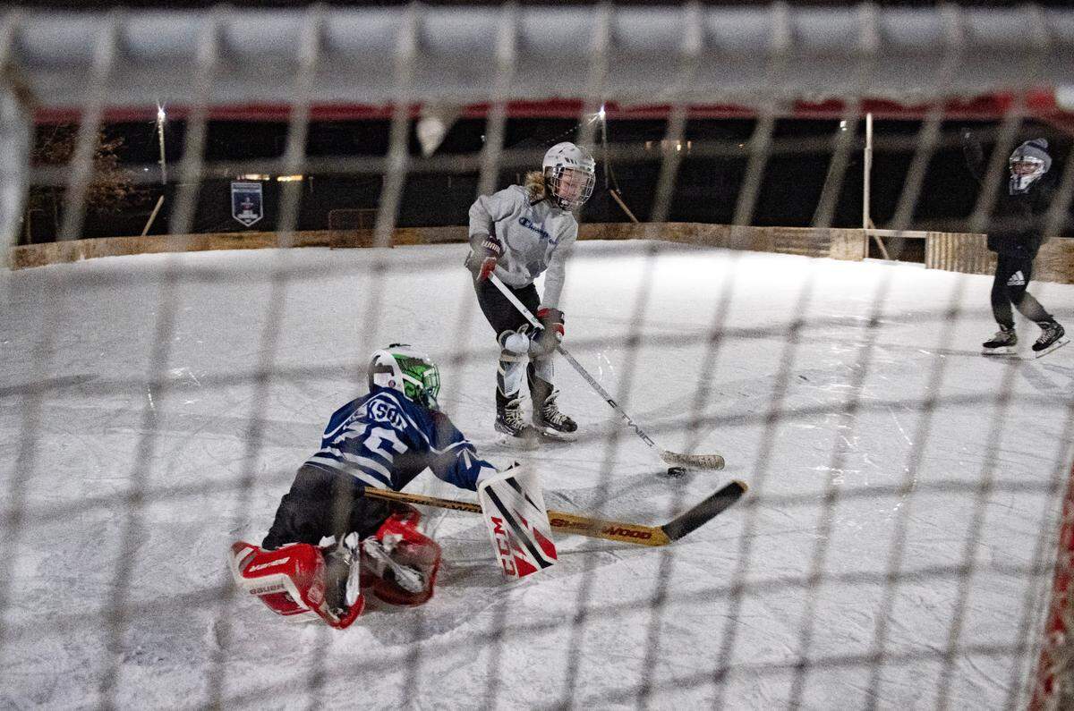 Blake Dickson takes a shot on goalie Atticus Dickson on their backyard ice rink in Lemont on Thursday, Feb. 20, 2025.