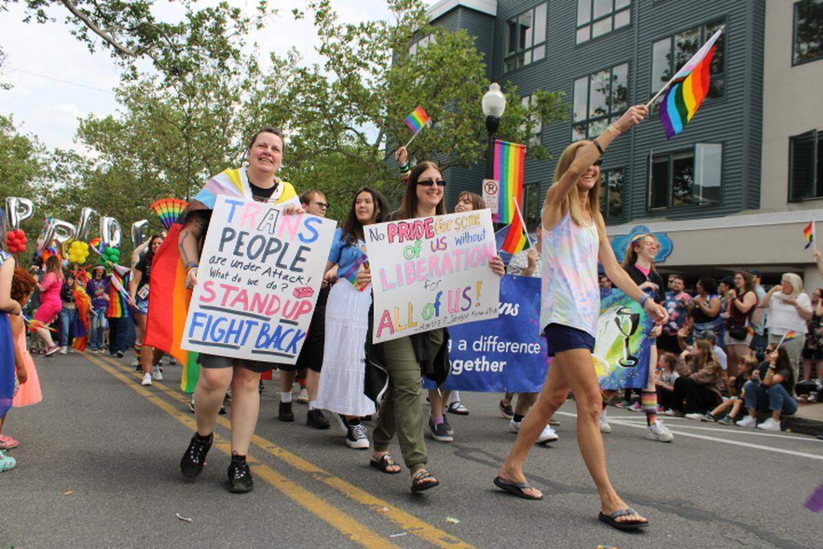 State College Pride Parade participants carry signs and wave flags as they walk down South Allen Street on Saturday, June 10, 2023.