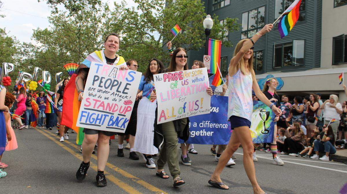 State College Pride Parade participants carry signs and wave flags as they walk down South Allen Street on Saturday, June 10, 2023.