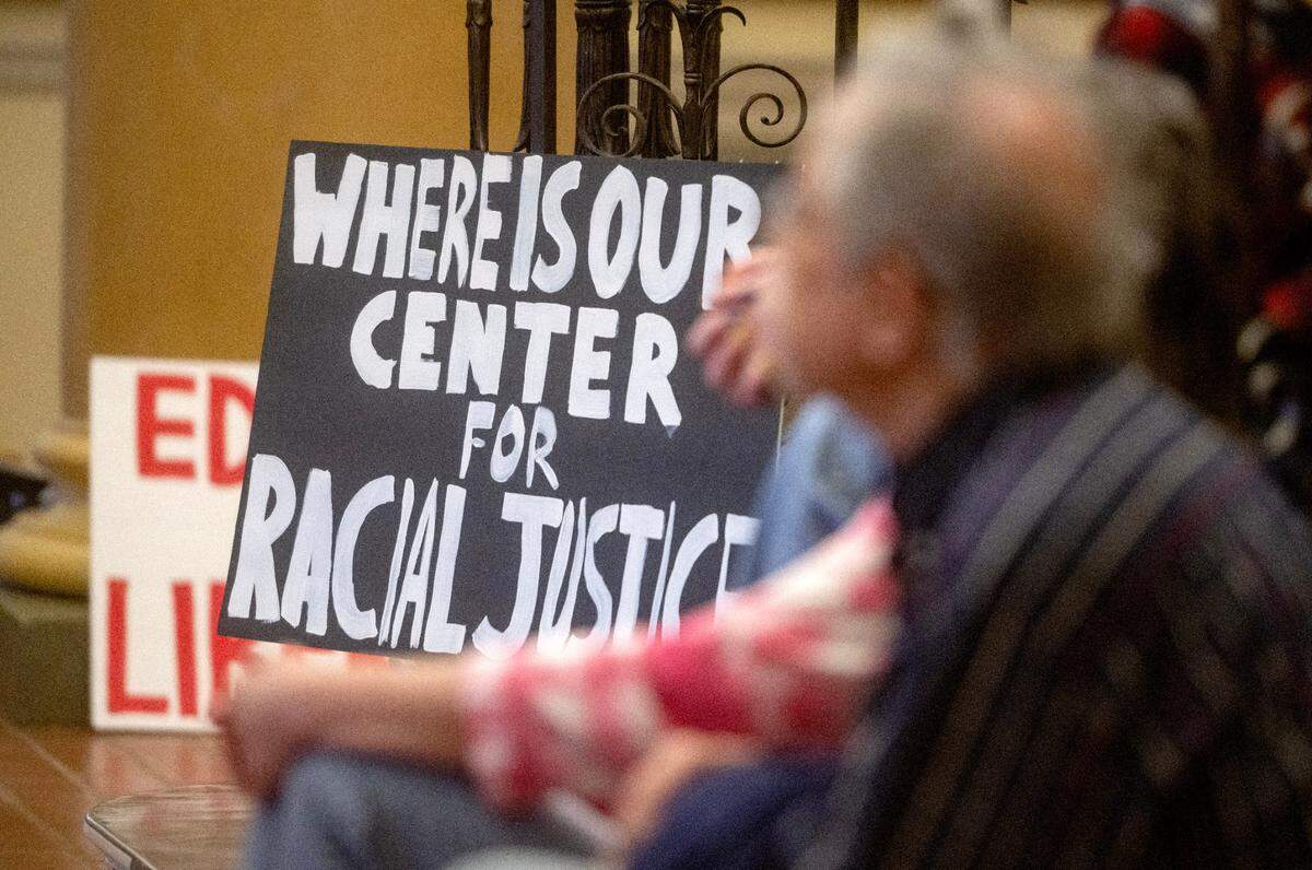 A poster asking “where is our center for racial justice” sits next to listeners of the read-in for social justice in the lobby of Penn State’s Old Main on Tuesday, April 16, 2024.