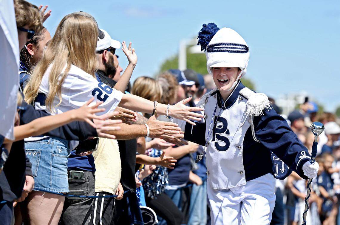 Penn State Blue Band drum major Ellie Sheehan high-five fans before team arrival outside of Beaver Stadium on Saturday, Aug. 30, 2025.  