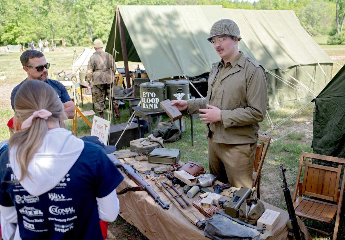 Kyle Marsh represents the 28th Infantry Division as he shows visitors what soldiers would get in their supper box during a World War II encampment at the Pennsylvania Military Museum on Saturday, May 27, 2023.