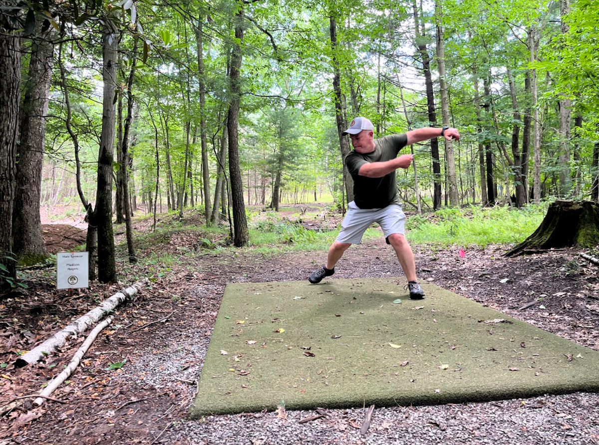 Ted Seibert, creator of the Wilderness City Disc Golf Course, is pictured throwing off the tee pad at the course’s ninth hole.