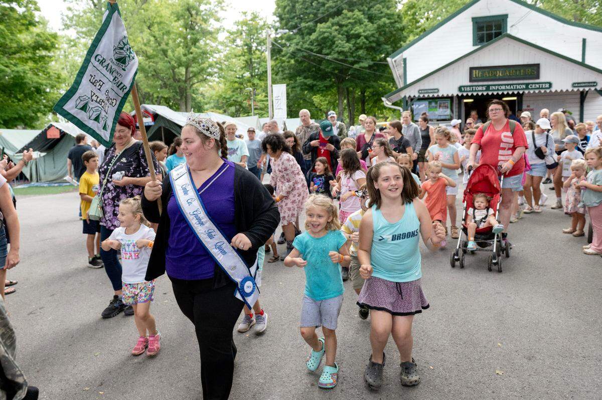 Grange Fair queen Kryslynn Ronk leads youngsters down Rhone Ave. in the chicken dance during the Centre County Grange Encampment and Fair on Monday, Aug. 19, 2024.  
