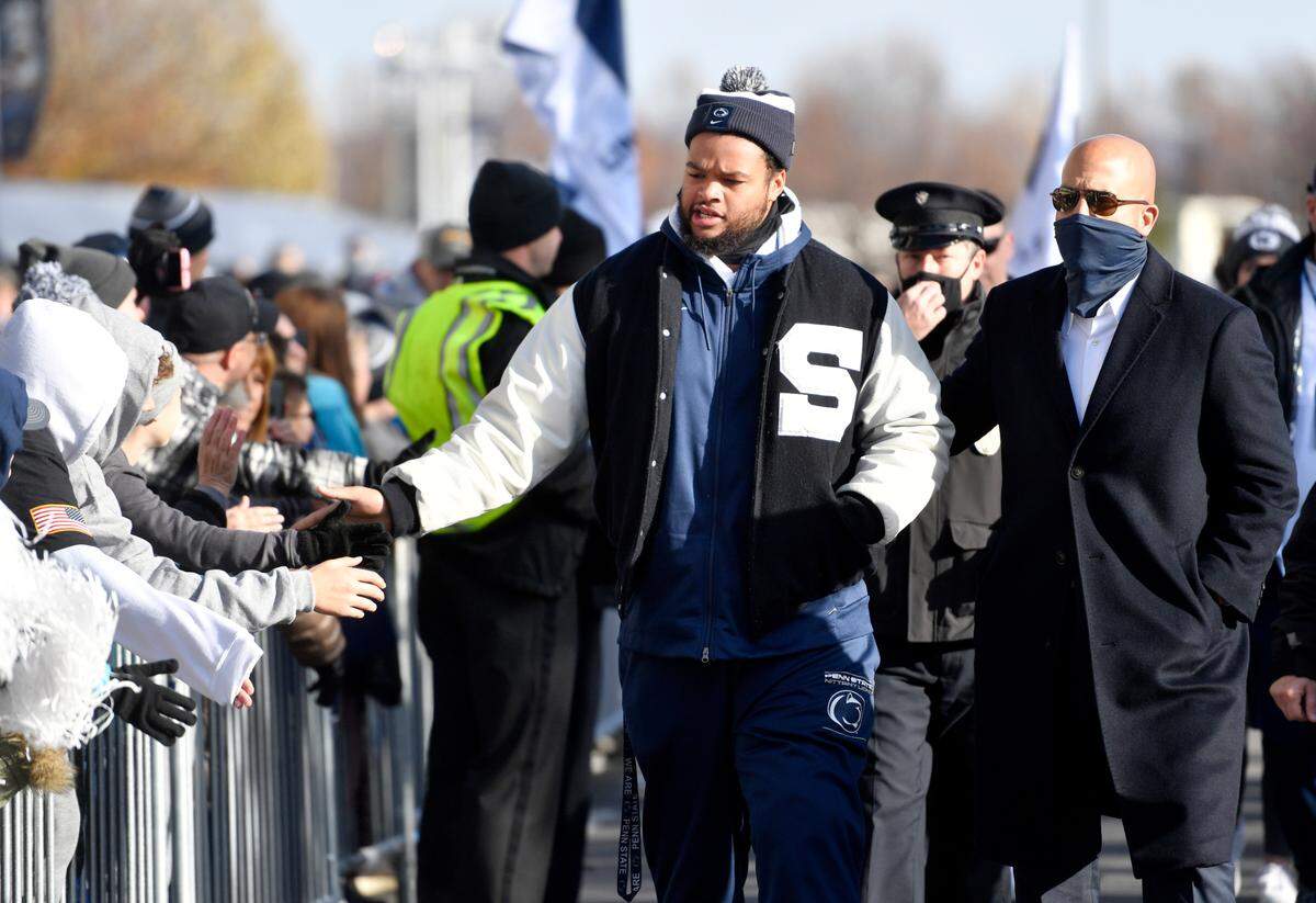 Penn State defensive tackle PJ Mustipher high-fives fans as he walks with coach James Franklin for team arrival on Saturday, Nov. 20, 2021.