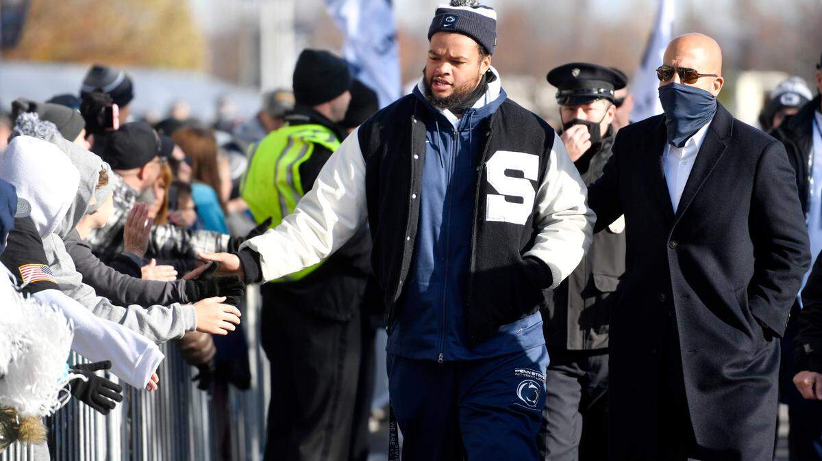 Penn State defensive tackle PJ Mustipher high-fives fans as he walks with coach James Franklin for team arrival on Saturday, Nov. 20, 2021.
