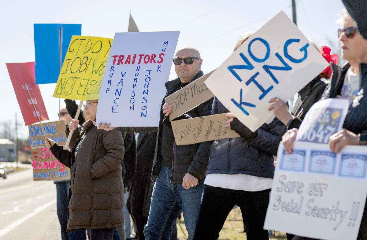 Ray Bilger holds a sign that says “Traitors” as he stands with fellow protesters who lined Benner Pike outside of U.S. Rep Glenn “GT” Thompson’s office on Tuesday, March 18, 2025.