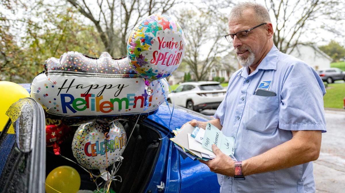 Balloons fill Jon Kolesar’s car as he holds a stack of cards from his last day as a mailman on Monday, Sept. 30, 2024. Some neighborhoods he delivered too including the Clover Highlands neighborhood decorated their mailboxes today to honor his retirement.