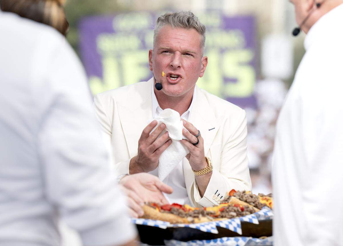 Pat McAfee wipes cheese off his face after taking a bite of a cheesesteak from Penn Steaks during ESPN’s College GameDay on Saturday, Sept. 27, 2025.  