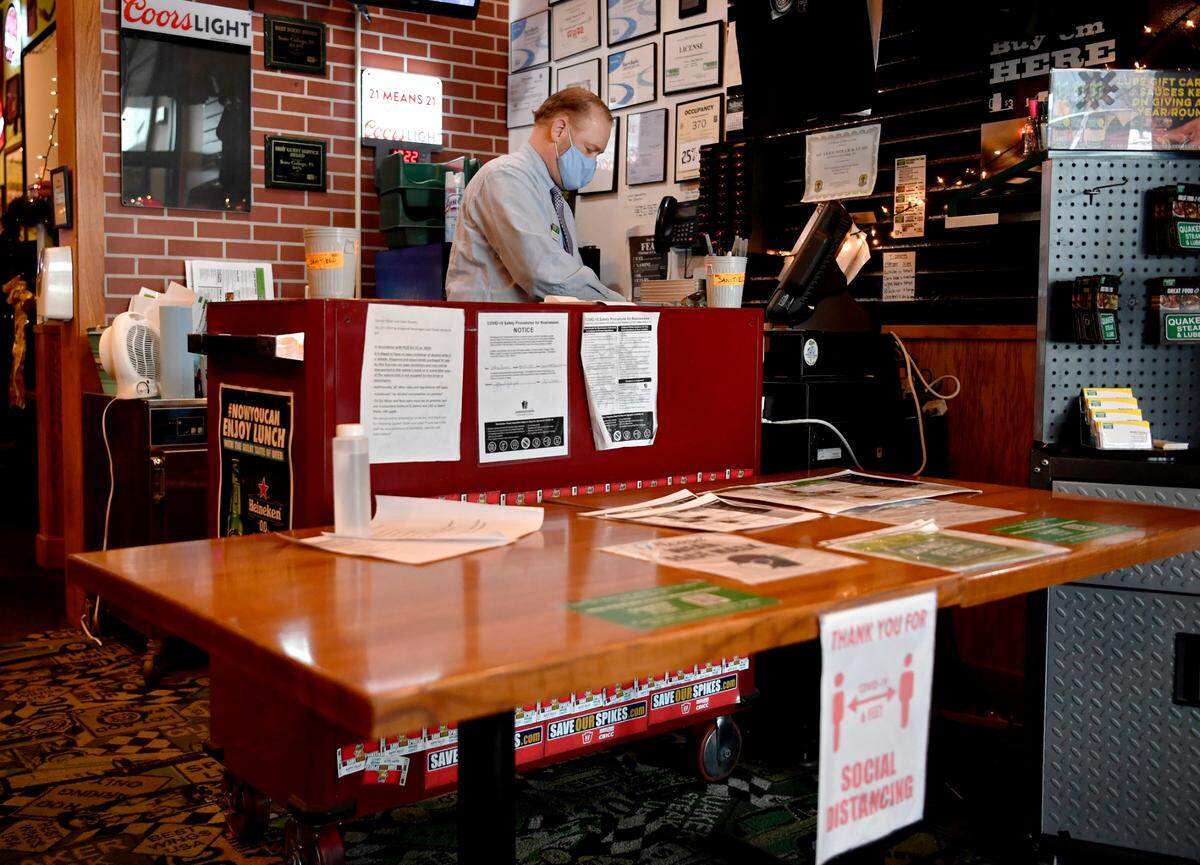 Jeff Powers, the general manager of Quaker Steak and Lube, stands at the host stand waiting for the phone to ring for takeout orders during the lunch hour on Tuesday, Dec. 22, 2020.