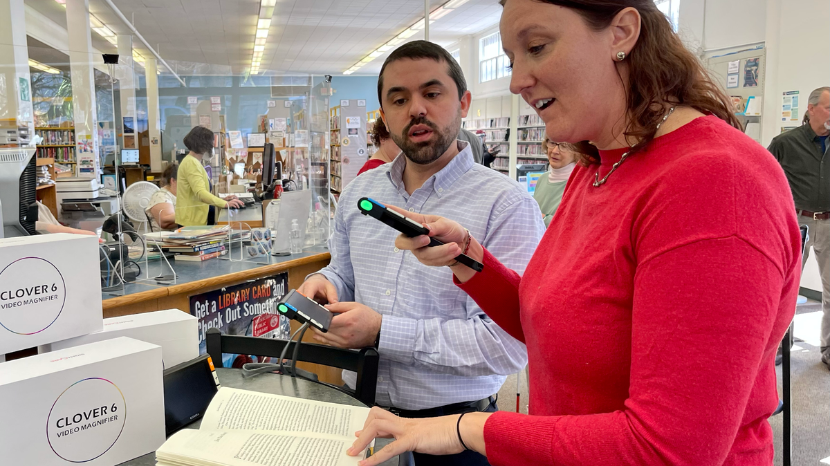 Lindsey Kurtz, chair of the Centre County Library board, learns how to use the handheld digital magnifier Monday, which was part of a donation to the library from North Central Sight Services. Centre County Library Branch Manager Nicholas Struble shows her to use it.