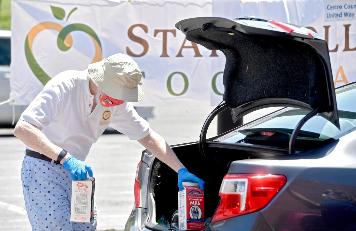A volunteer from the State College Downtown Rotary helps to hand load two half galloons of milk into a car during a distribution event outside of the Nittany Mall on Tuesday, May 26, 2020. The event was organized by the State College Food Bank, Vale Wood Farms, the State College Downtown Rotary, Penn State Extension and the Centre County Farm Bureau.