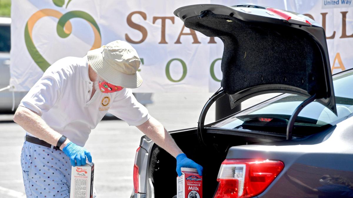 A volunteer from the State College Downtown Rotary helps to hand load two half gallons of milk into a car during a distribution event outside of the Nittany Mall on Tuesday, May 26, 2020.