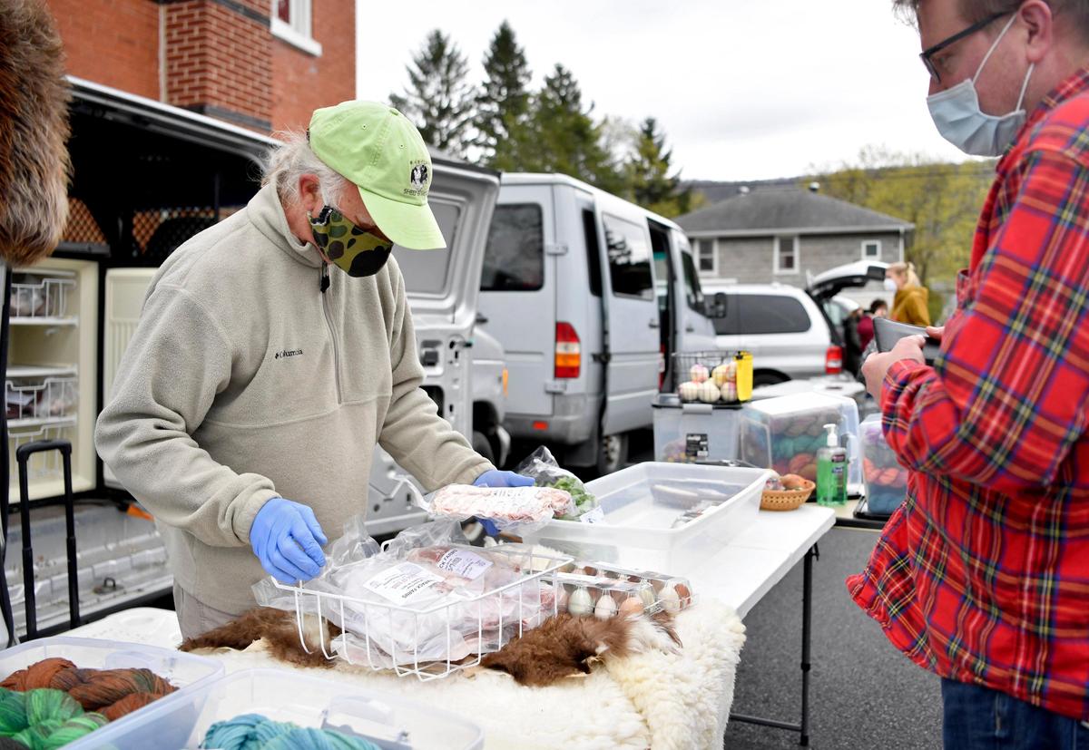 Michael Arthur of Tamarak Farm from Spring Mills helps a costumer pick some pork at the Boalsburg Farmers Market on Tuesday April 28, 2020.