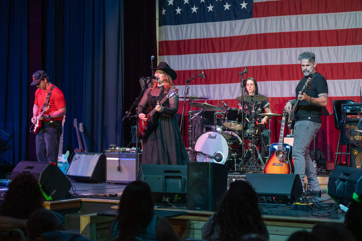 Caryn Dixon performs with three other musicians in front of an American flag