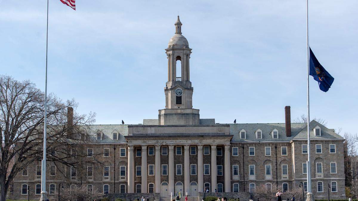 Students sit outside of Old Main on the Penn State campus on Tuesday, March 30, 2021.