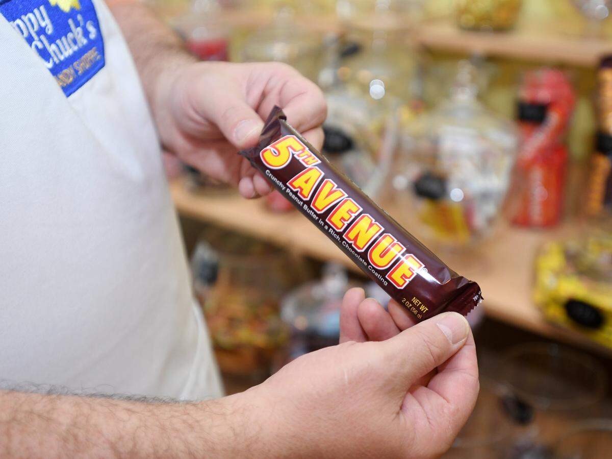 Pappy Chuck's Candy Shoppe owner Chuck Kormanski holds up a 5th Avenue bar on July 1 at his store in Bellefonte.