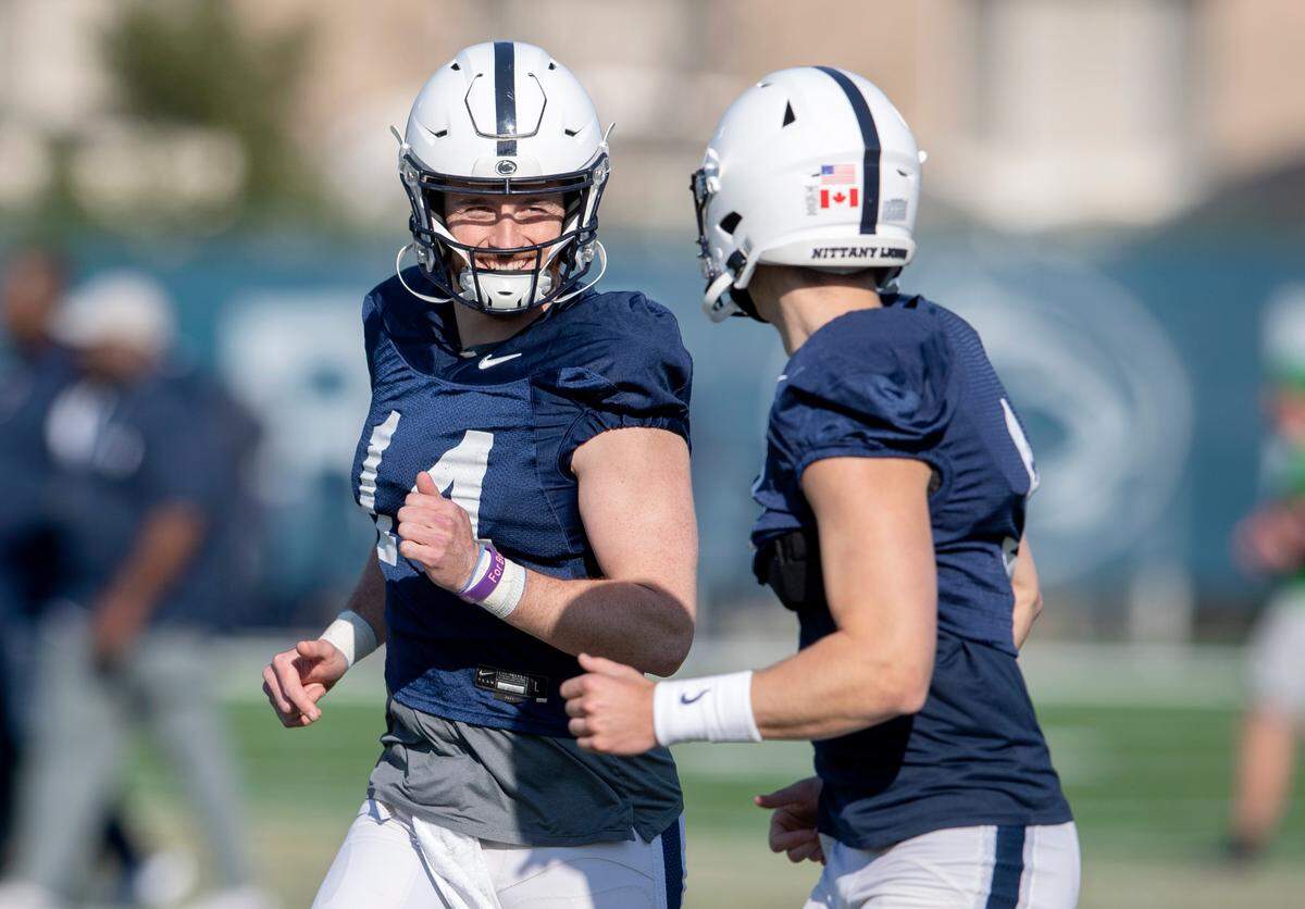 Penn State quarterbacks Sean Clifford and Christian Veilleux laugh together as they jog to the next drill at the first day of spring practice on Monday, March 21, 2022.
