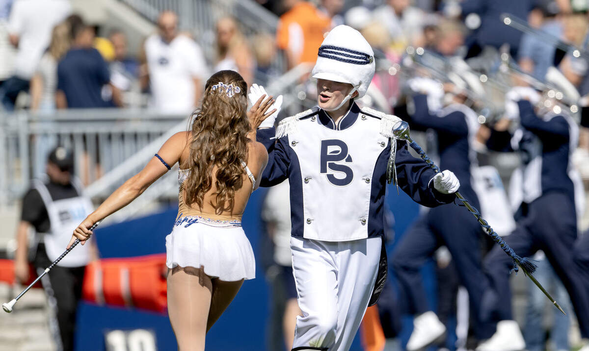 Penn State Blue Band drum major Ellie Sheehan high-fives Blue Sapphire Mackenzie Bronk during the pregame show on Saturday, Aug. 30, 2025.  