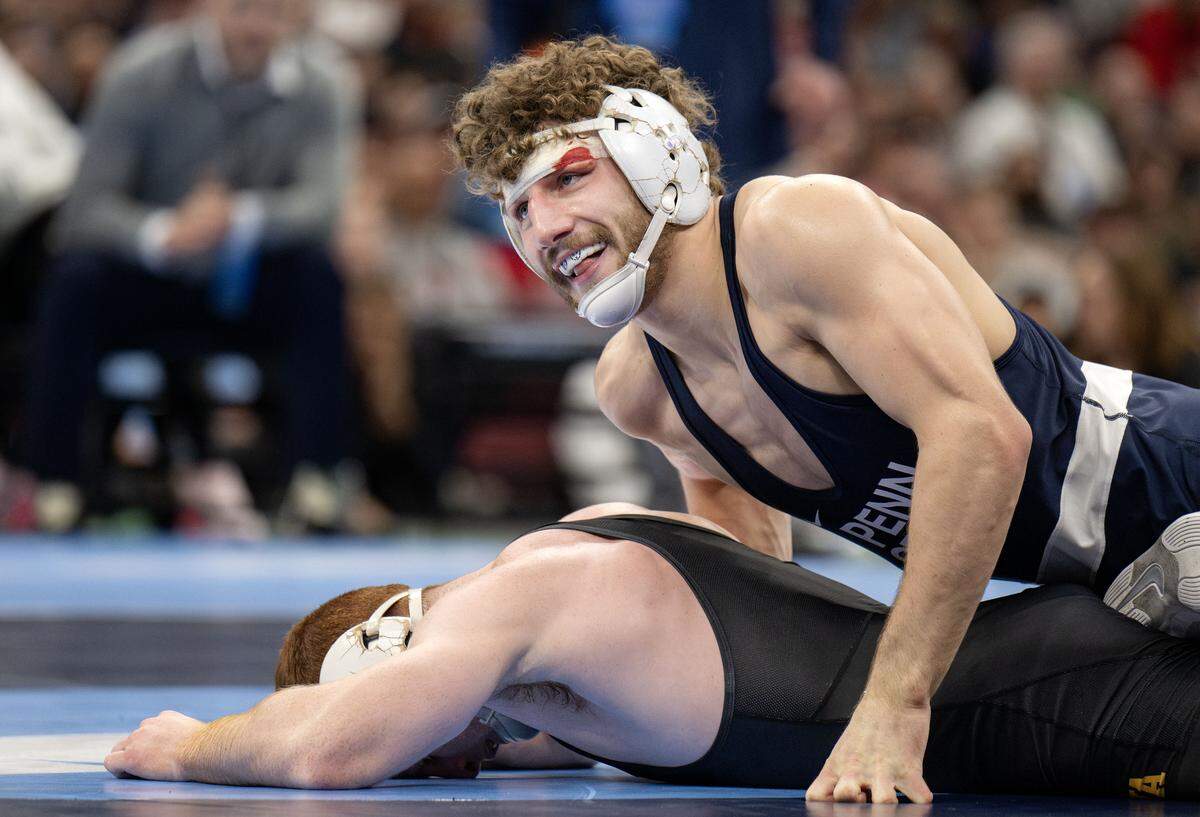 Iowa’s Michael Caliendo lays in defeat as Penn State's Mitchell Mesenbrink smiles toward his family after winning the 165-pound championship bout at the NCAA wrestling championships on Saturday, March 21, 2026.