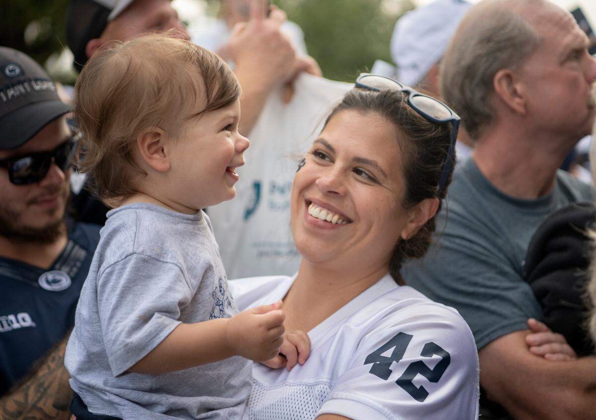 Dylan Rinaldi, 14 months, giggles at the Nittany Lion as he pumps up the crowd for the Penn State football team to arrive for the game.
