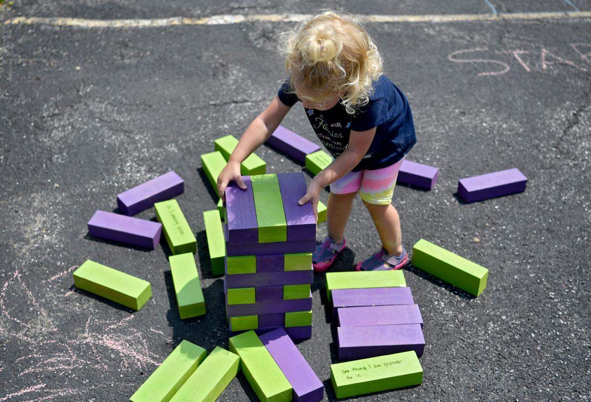 Avery Foltz, 1, unstacks blocks outside of Trinity UCC in Centre Hall on Monday during a stop on the Free to be Me tour from the YMCA of Centre County and Jana Marie Foundation.