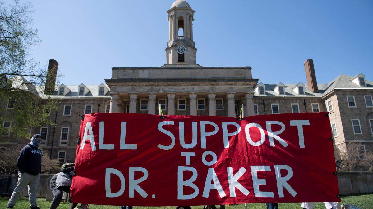Organizers set up a banner during a Thursday rally to protest the termination process for Penn State professor Oliver Baker.