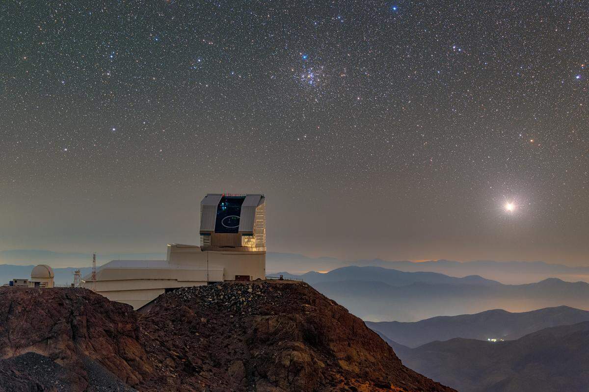 NSF–DOE Vera C. Rubin Observatory is seen with its dome open during First Look observation activities in April 2025. M41, the Little Beehive Cluster, can be seen over the telescope.