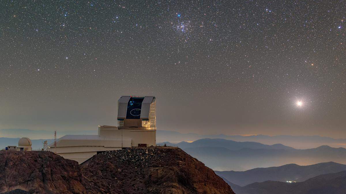 NSF–DOE Vera C. Rubin Observatory is seen with its dome open during First Look observation activities in April 2025. M41, the Little Beehive Cluster, can be seen over the telescope.