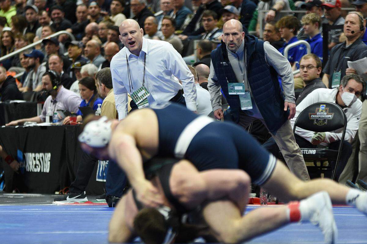 Penn State head coach Cael Sanderson and assistant coach Casey Cunningham watch Max Dean’s 197-pound semifinals bout on Friday at Little Caesars Arena in Detroit. Sanderson and his staff have led the Nittany Lions to 9 NCAA titles in the last 11 contested events.